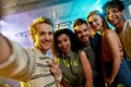 Close up shot of young men and women smiling while taking selfie. Multiracial group of friends hanging out at party in Royalty Free Stock Photo