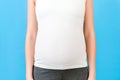 Close up shot of young pregnant woman`s belly in home clothing at blue background. Pregnancy concept. Copy space Royalty Free Stock Photo