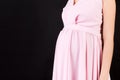 Close up shot of young pregnant woman`s belly in pink dress at black background. Pregnancy concept. Copy space Royalty Free Stock Photo