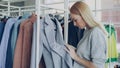 Close-up shot of young woman choosing coat in shop. First she is examining fabric , looking at buttons, underlinimg and Royalty Free Stock Photo