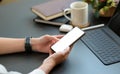 Close-up shot of a Young woman using a blank screen smartphone with a laptop and coffee on the desk Royalty Free Stock Photo