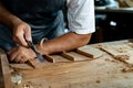 Close-up of guitar luthier using chisel to shave bracing of acoustic guitar