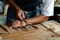 Close-up of guitar luthier using chisel to shave bracing of acoustic guitar