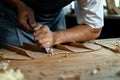 Close-up of guitar luthier using chisel to shave bracing of acoustic guitar