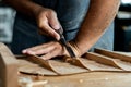 Close-up of guitar luthier using chisel to shave bracing of acoustic guitar