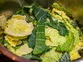 Shredded green savoy cabbage being washed in a stainless steel colander