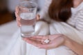 Close Up on sick asian woman holding medicine and glass of water in her hand Royalty Free Stock Photo