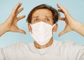 Close up sick young man handsome wearing medical mask and white shirt isolated on blue background. Concept of sickness