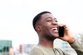 Close up side of happy african american man laughing and with cellphone outdoors Royalty Free Stock Photo