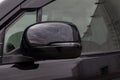 Close-up of the side left mirror with led turn signal and window of the car body black SUV on the street parking after washing and Royalty Free Stock Photo