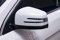 Close-up of the side left mirror with turn signal repeater and window of the car body white SUV on the street parking after Royalty Free Stock Photo