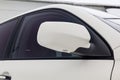 Close-up of the side left mirror with turn signal repeater and window of the car body white SUV on the street parking after Royalty Free Stock Photo