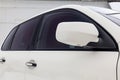 Close-up of the side left mirror with turn signal repeater and window of the car body white SUV on the street parking after Royalty Free Stock Photo