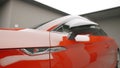 Close up of side mirror and a door of a red new race car parked in garage. Action. Beautiful clean and shiny expensive Royalty Free Stock Photo