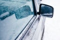 Close-up of side mirror of snow covered blue car