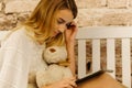 The close-up side portrait of the girl using the tablet while holding the Teddy bear. Royalty Free Stock Photo