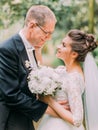 CLose-up side portrait of the happy newlyweds in the garden. The bride is stroking the cheek of the groom. Royalty Free Stock Photo