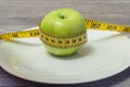 Close up side profile view photo of flawless beautiful juicy hard apple. Photo of tape measure coiled around the apple on a white Royalty Free Stock Photo