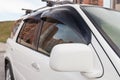 A close-up of the side right rear-view mirror and the car body window of a white crossover in a street parking lot after washing Royalty Free Stock Photo