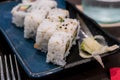 A close-up side shoot of Uramaki sushi rolls with fresh salmon, avocado and philadelphia cheese, covered with sesame seeds