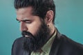 Close up side view of bearded man with a man bun hairstyle posing in a studio wearing a suit and earrings whilst looking down, Royalty Free Stock Photo