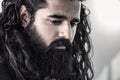 Close up side view of bearded man with long hair posing in a studio whilst looking down emotionally, male model fashion portrait Royalty Free Stock Photo