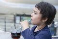 Close up side view of Cute kid drinking cold drink in coffee shop by the sea, Little boy drinking soda with straw. Child drinking Royalty Free Stock Photo
