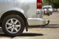 Close-up side view detail of silver passenger medium size luxury minibus van with tow-bar parked on summer sunny city street