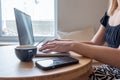 Close up side view of female using her laptop at a cafe. Lateral shot of young woman sitting at a table with a cup of Royalty Free Stock Photo