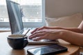 Close up side view of female using her laptop at a cafe. Lateral shot of young woman sitting at a table with a cup of Royalty Free Stock Photo