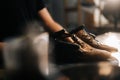 Close-up side view of hands of shoemaker shoemaker in black gloves holding old worn light brown leather shoes Royalty Free Stock Photo