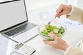 Close-up side view image, A businesswoman eating healthy salad bowl at her office desk Royalty Free Stock Photo