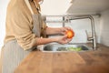 A woman washing vegetables at a sink and preparing fresh vegetable for her food in the kitchen Royalty Free Stock Photo