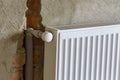 Close-up side view of isolated installed heating radiator on brick rough plastered wall in an empty room of a newly built Royalty Free Stock Photo