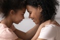 Close up side view mom and daughter touching foreheads.