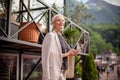 Pleasant housewife is holding tablet in front of her beautiful house