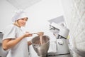 Close up side view photo of young girl confectioner chef, checking the mixed dough, holding a spatula, mixing the dough