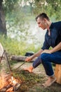 Close up side view photo. young handsome man is setting fire to the stick. Royalty Free Stock Photo