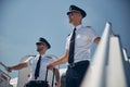 Confident males wearing sunglasses with rolling bags looking down on the moving ramp