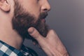 Close up side view portrait of minded man touching his beard