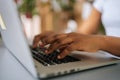 Close-up side view of unrecognizable African-American business woman typing on laptop keyboard sitting at home office Royalty Free Stock Photo