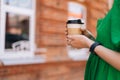 Close-up side view of unrecognizable young woman holding takeaway coffee cup outdoors in city street in summer sunny day Royalty Free Stock Photo