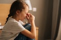 Close-up side view of upset little girl crying sitting alone on bed in bedroom. Concept of child depression. Royalty Free Stock Photo