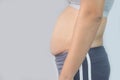 Close-up side view of woman excessive belly fat on gray background. Woman fat belly. Obesity and Overweight Concept