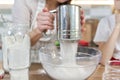 Close-up sifting flour through metal sieve cup