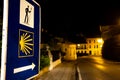 Close up of sign with arrow and yellow shell pointing the Camino de Santiago direction at night, which you need to follow to reach Royalty Free Stock Photo