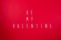 Phrase be my valentine written on red background . top view