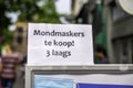 Close-up of a sign poster announcing in Dutch that medical face masks against the coronavirus are available at a local shop