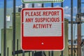 Close up of a sign that reads Please Report Any Suspicious Activity