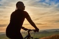 Close-up of silhouette of cyclist standing with bike against beautiful sunset.